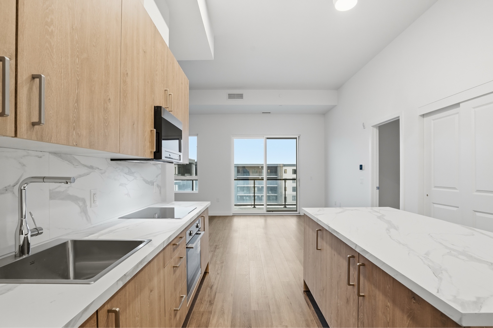 Marbella residence kitchen – marble island, light wood cabinetry, balcony view